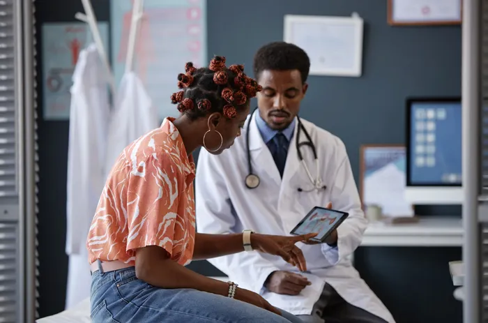 A patient and a doctor reviewing health screening results together on a tablet